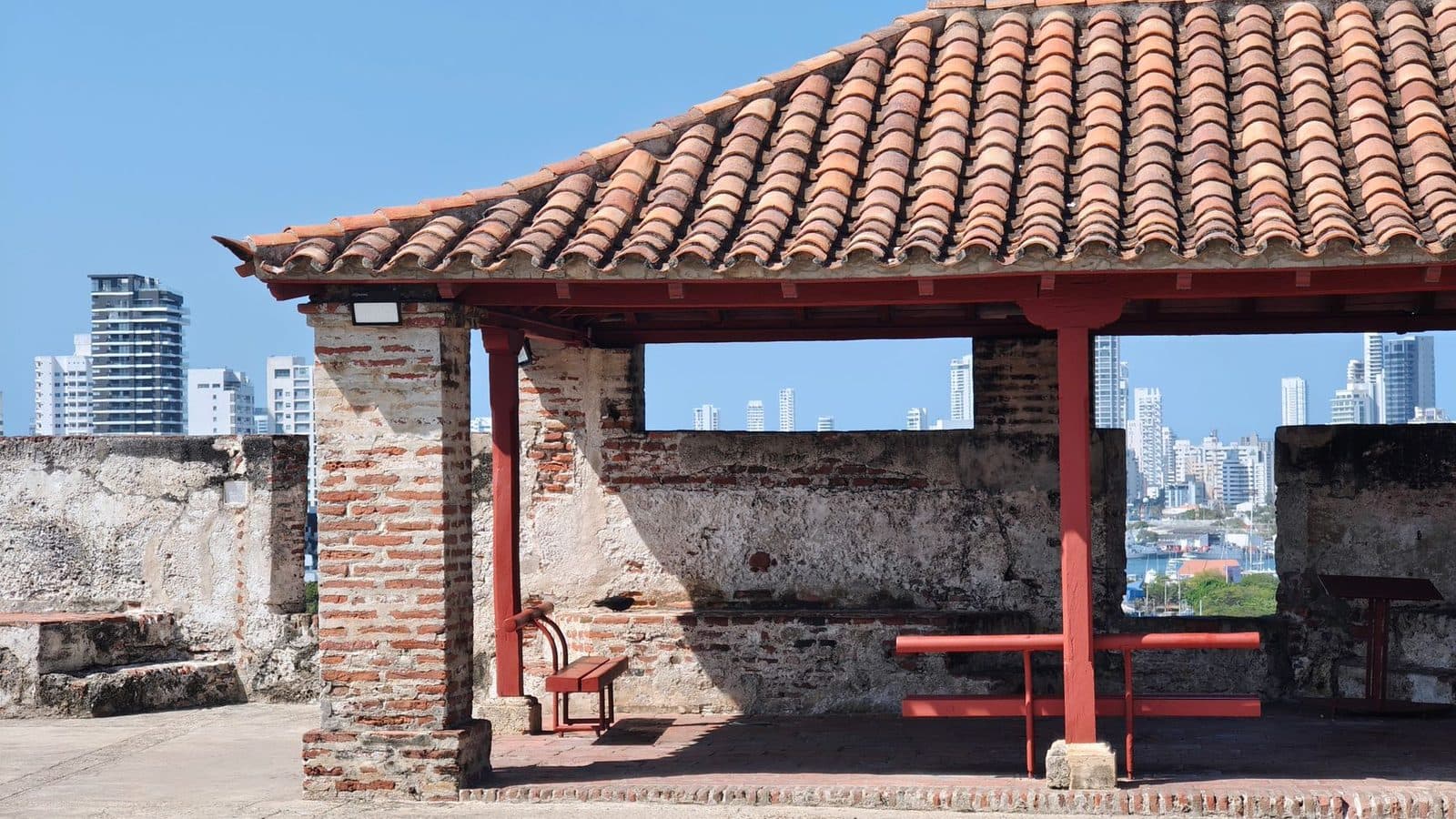 Guarita de pedra na muralha da cidade antiga de Cartagena, com prédios modernos ao fundo