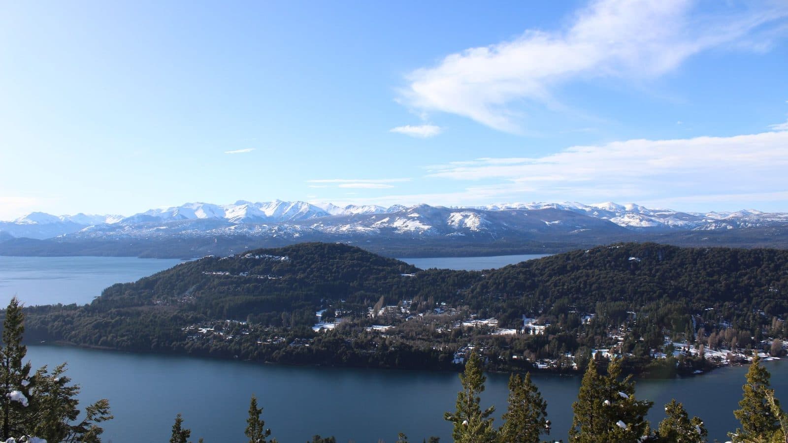 Lago Nahuel Huapi, florestas e montanhas com neve em Bariloche, sob céu azul
